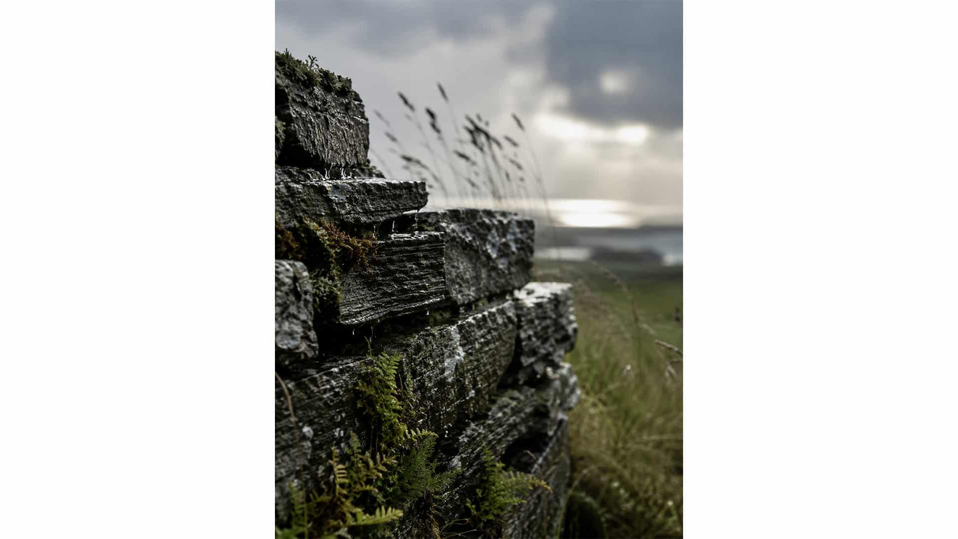 Mur de pierre sèche sous la pluie face à la mer, paysage du Finistère