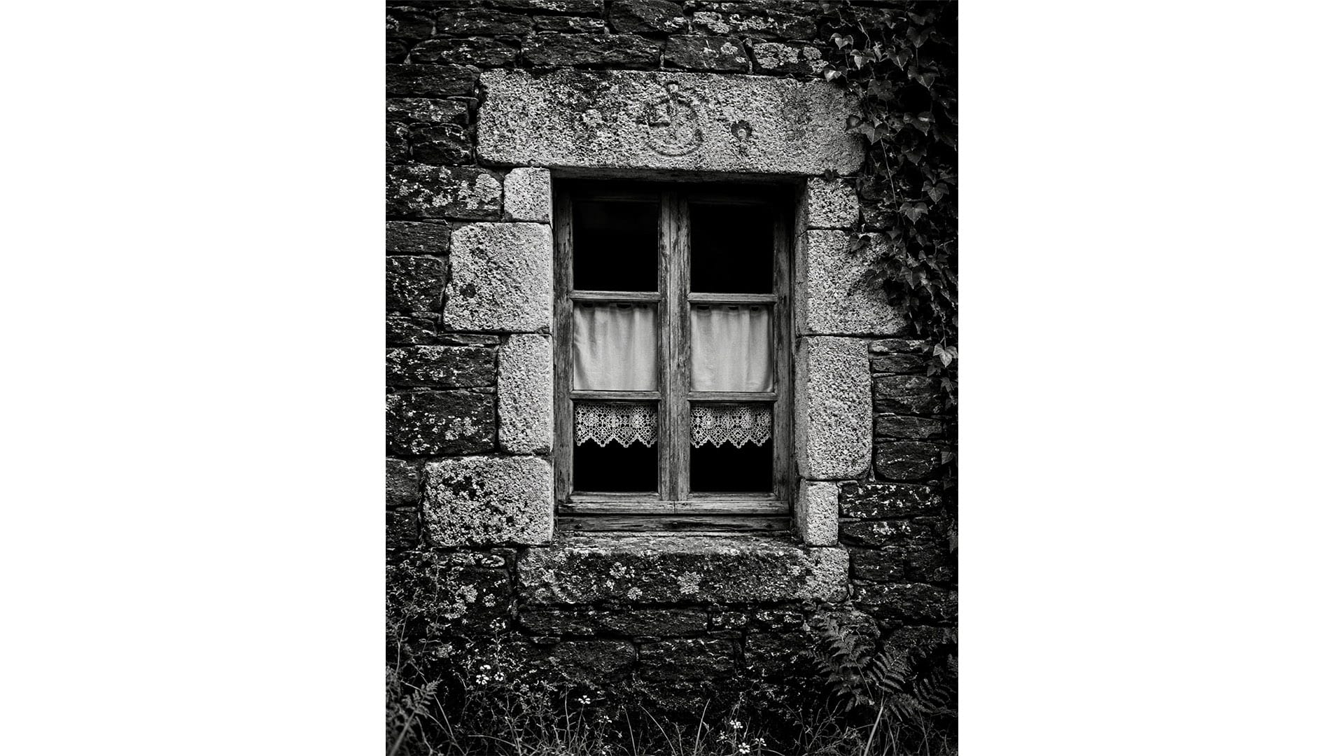 Fenêtre ancienne à meneaux de bois dans une bâtisse en pierre, Bretagne